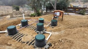 Residential OWTS installation with green risers, PVC manifold piping, and control panel enclosure — Solid State Septic