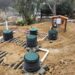 Residential OWTS installation with green risers, PVC manifold piping, and control panel enclosure — Solid State Septic
