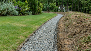 Gravel-filled drainage trench beside excavated soil on a residential lawn during leach field work — Solid State Septic