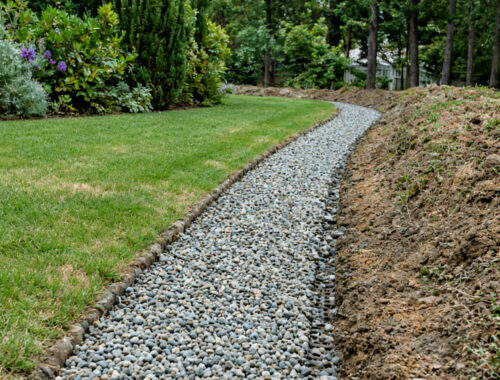 Gravel-filled drainage trench beside excavated soil on a residential lawn during leach field work — Solid State Septic
