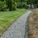 Gravel-filled drainage trench beside excavated soil on a residential lawn during leach field work — Solid State Septic