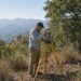 Land surveyor with total station on a dry San Diego County hillside during OWTS site engineering — Solid State Septic