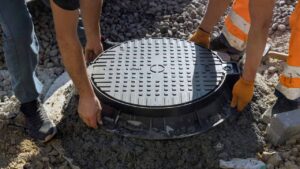Cast-iron hatch being set into a concrete septic access well during installation — Solid State Septic