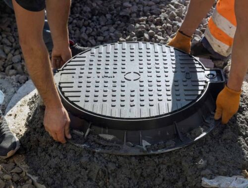 Cast-iron hatch being set into a concrete septic access well during installation — Solid State Septic