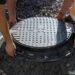 Cast-iron hatch being set into a concrete septic access well during installation — Solid State Septic