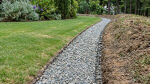 Grassy residential drainage corridor with stormwater channeling away from landscaped yard — Solid State Septic