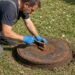 Septic technician inspecting a residential tank lid