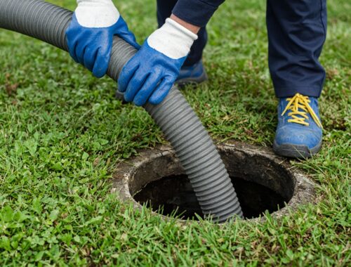 Technician pumping a septic tank in a grassy yard