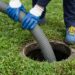 Technician pumping a septic tank in a grassy yard